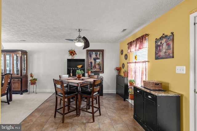 dining space with ceiling fan, light carpet, and a textured ceiling