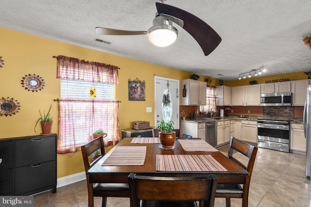 tiled dining room featuring ceiling fan, sink, and a textured ceiling