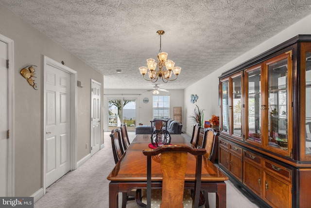 carpeted dining room with ceiling fan with notable chandelier and a textured ceiling