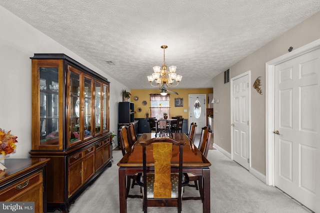 carpeted dining room featuring a textured ceiling and an inviting chandelier