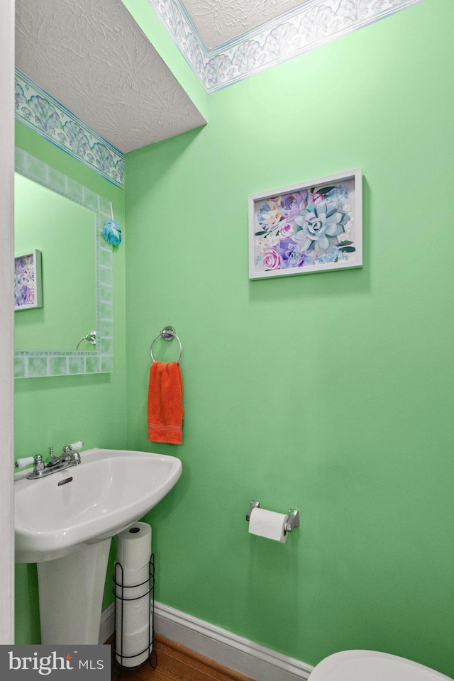 bathroom featuring wood-type flooring and a textured ceiling