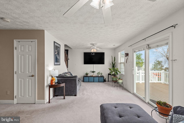 living room with a textured ceiling, carpet floors, and ceiling fan