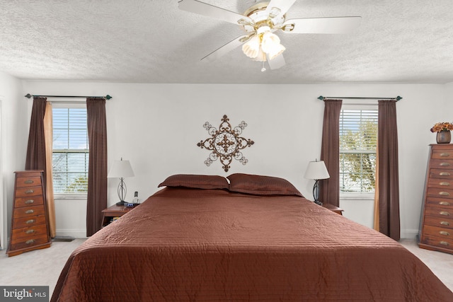 carpeted bedroom with ceiling fan, a textured ceiling, and multiple windows