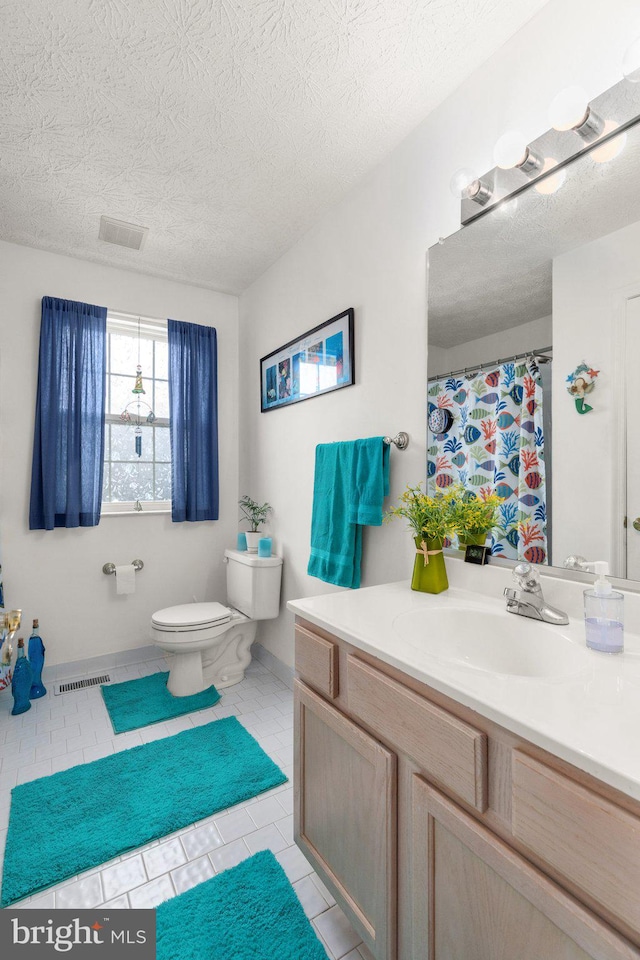 bathroom with tile patterned flooring, vanity, toilet, and a textured ceiling