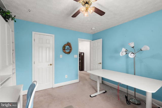 home office featuring ceiling fan, light colored carpet, and a textured ceiling