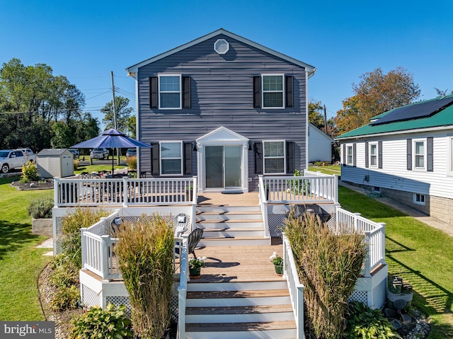 view of front of house with a front yard, a storage shed, and a wooden deck