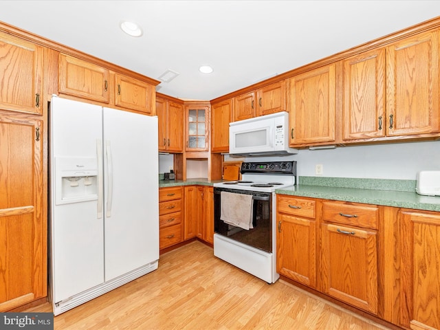 kitchen with white appliances and light hardwood / wood-style flooring