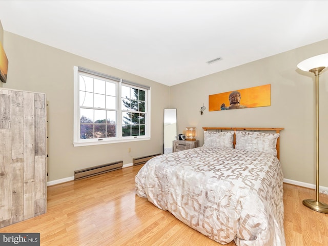 bedroom with a baseboard radiator and wood-type flooring