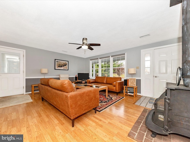 living room featuring a wood stove, ceiling fan, and hardwood / wood-style flooring