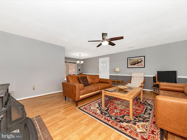 living room with hardwood / wood-style floors and ceiling fan with notable chandelier