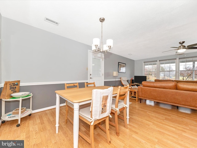 dining room with light hardwood / wood-style floors and ceiling fan with notable chandelier