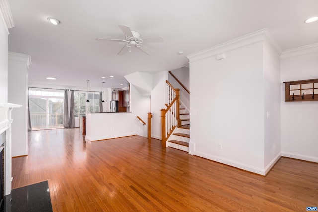 unfurnished living room featuring hardwood / wood-style flooring, ceiling fan, and crown molding