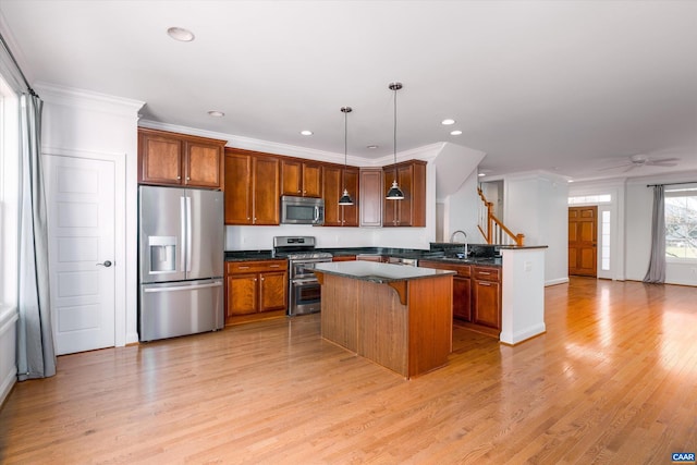 kitchen featuring a breakfast bar, crown molding, hanging light fixtures, light hardwood / wood-style flooring, and appliances with stainless steel finishes