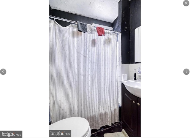 full bathroom featuring vanity, shower / bath combination with curtain, toilet, and tile walls