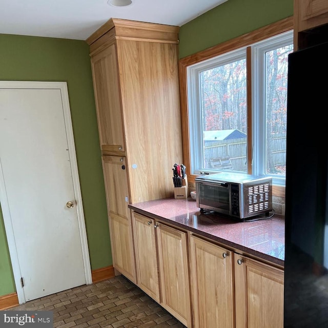 kitchen with light brown cabinets and black refrigerator