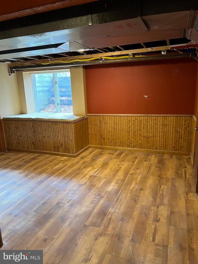 basement with hardwood / wood-style flooring and wooden walls