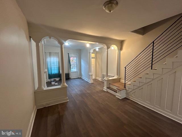 corridor with decorative columns and dark hardwood / wood-style floors