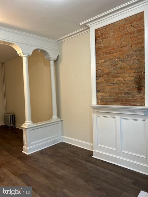 interior space featuring dark hardwood / wood-style flooring, crown molding, and ornate columns