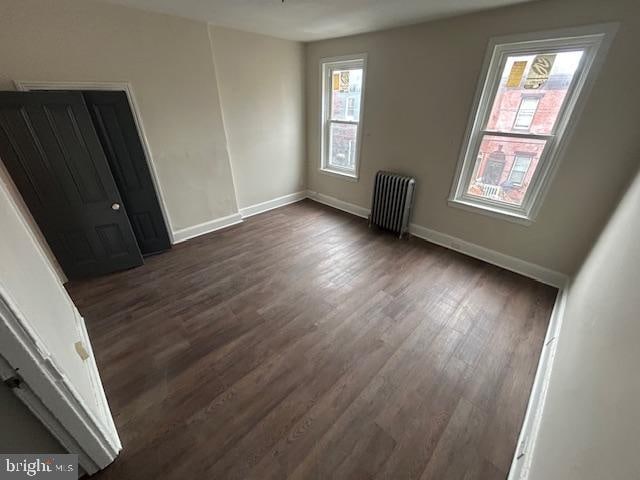 spare room featuring dark hardwood / wood-style floors and radiator