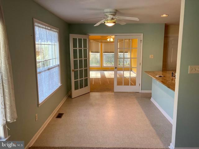 unfurnished dining area with ceiling fan, light carpet, and french doors