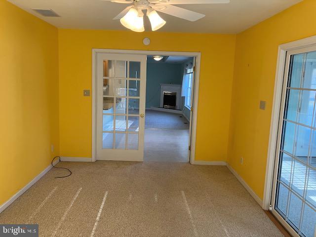 carpeted empty room featuring ceiling fan and french doors