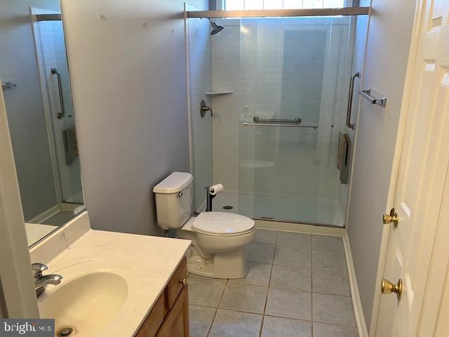 bathroom with tile patterned floors, vanity, toilet, and a shower with door