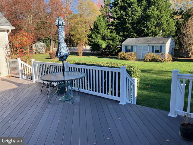 wooden terrace featuring a yard and an outdoor structure