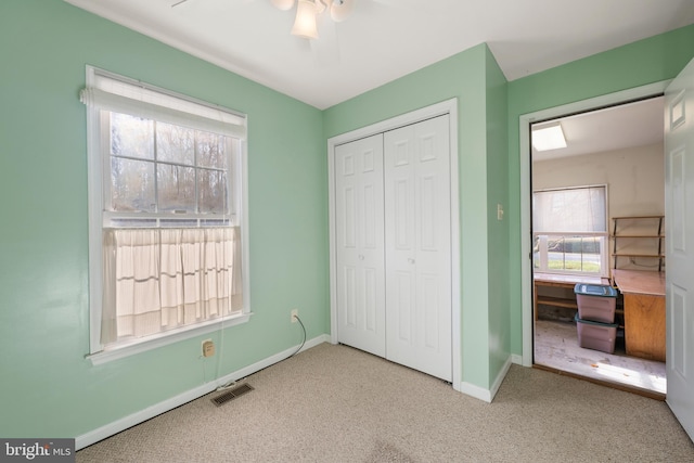 unfurnished bedroom with ceiling fan, a closet, light carpet, and multiple windows