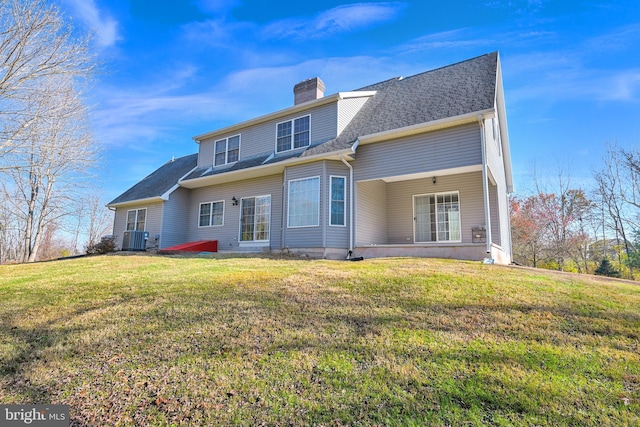 back of property with central air condition unit and a lawn