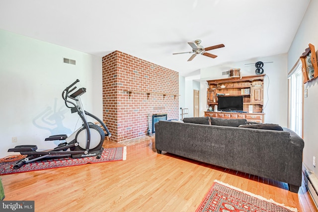 living room featuring ceiling fan, a fireplace, and hardwood / wood-style flooring