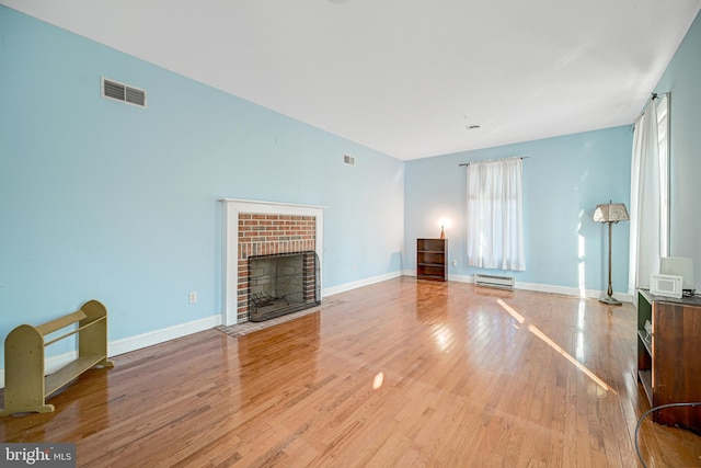 unfurnished living room with a fireplace, light hardwood / wood-style flooring, and baseboard heating