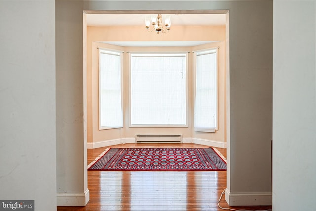 doorway featuring baseboard heating, wood-type flooring, and a notable chandelier