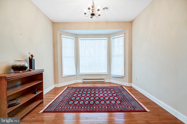 entryway with wood-type flooring, a baseboard radiator, and an inviting chandelier