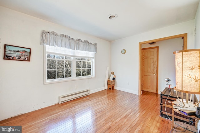 empty room featuring a baseboard radiator and wood-type flooring