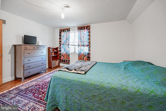 bedroom with hardwood / wood-style flooring and lofted ceiling