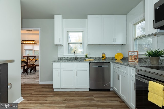 kitchen featuring white cabinets, stainless steel appliances, a wealth of natural light, and hardwood / wood-style floors