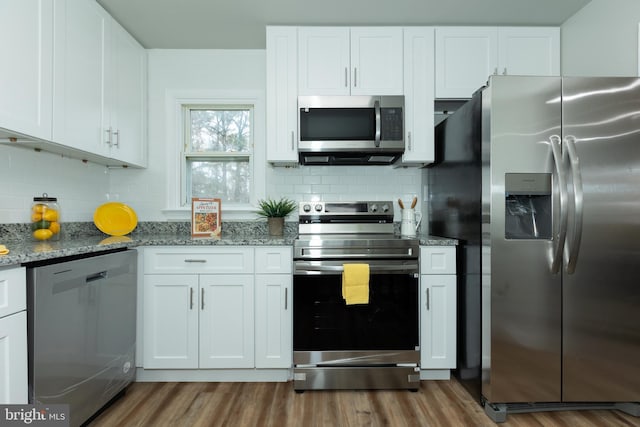 kitchen with white cabinets, hardwood / wood-style flooring, stone countertops, and appliances with stainless steel finishes