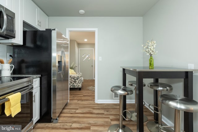 kitchen with white cabinetry, stainless steel appliances, and light wood-type flooring