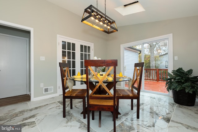 dining room with vaulted ceiling with skylight and a chandelier