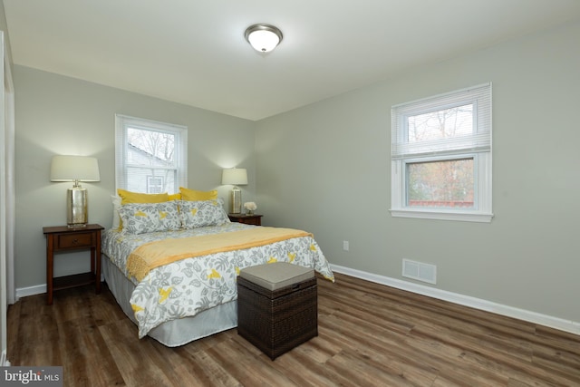 bedroom with multiple windows and dark wood-type flooring