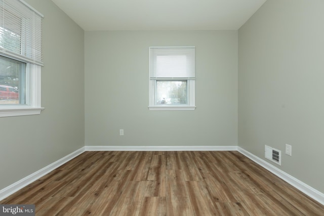 empty room with hardwood / wood-style floors and a healthy amount of sunlight