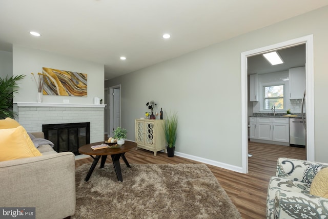 living room with dark hardwood / wood-style floors, sink, and a brick fireplace