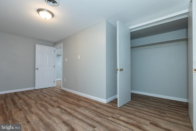 unfurnished bedroom featuring wood-type flooring and a closet