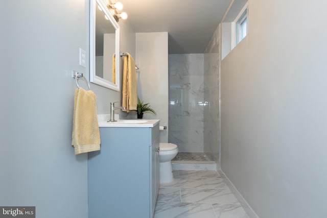 bathroom with tiled shower, vanity, and toilet