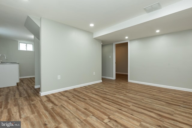 basement featuring light hardwood / wood-style flooring and sink