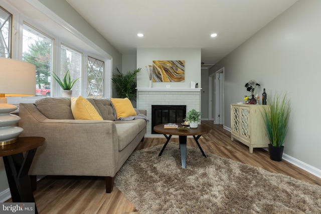 living room with hardwood / wood-style flooring and a brick fireplace