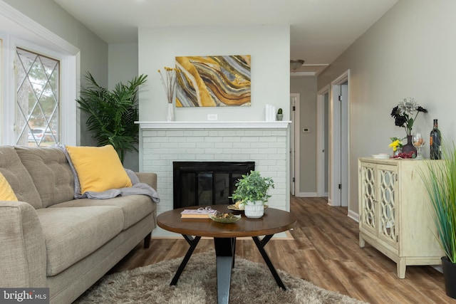 living room with a brick fireplace and hardwood / wood-style flooring