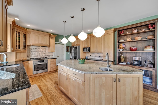 kitchen featuring sink, stainless steel appliances, an island with sink, light hardwood / wood-style floors, and decorative light fixtures