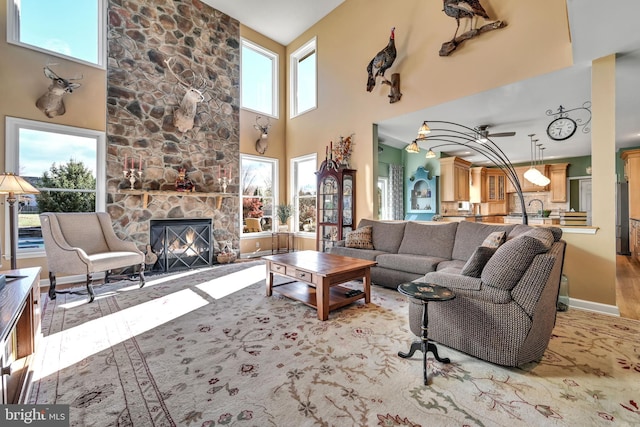 living room with a fireplace, a towering ceiling, a wealth of natural light, and ceiling fan