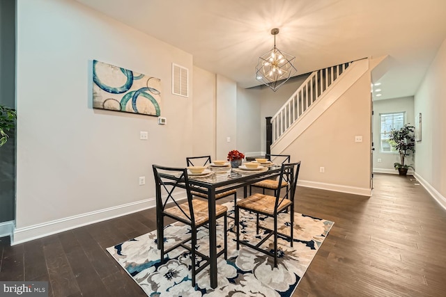 dining area with dark wood-type flooring and an inviting chandelier